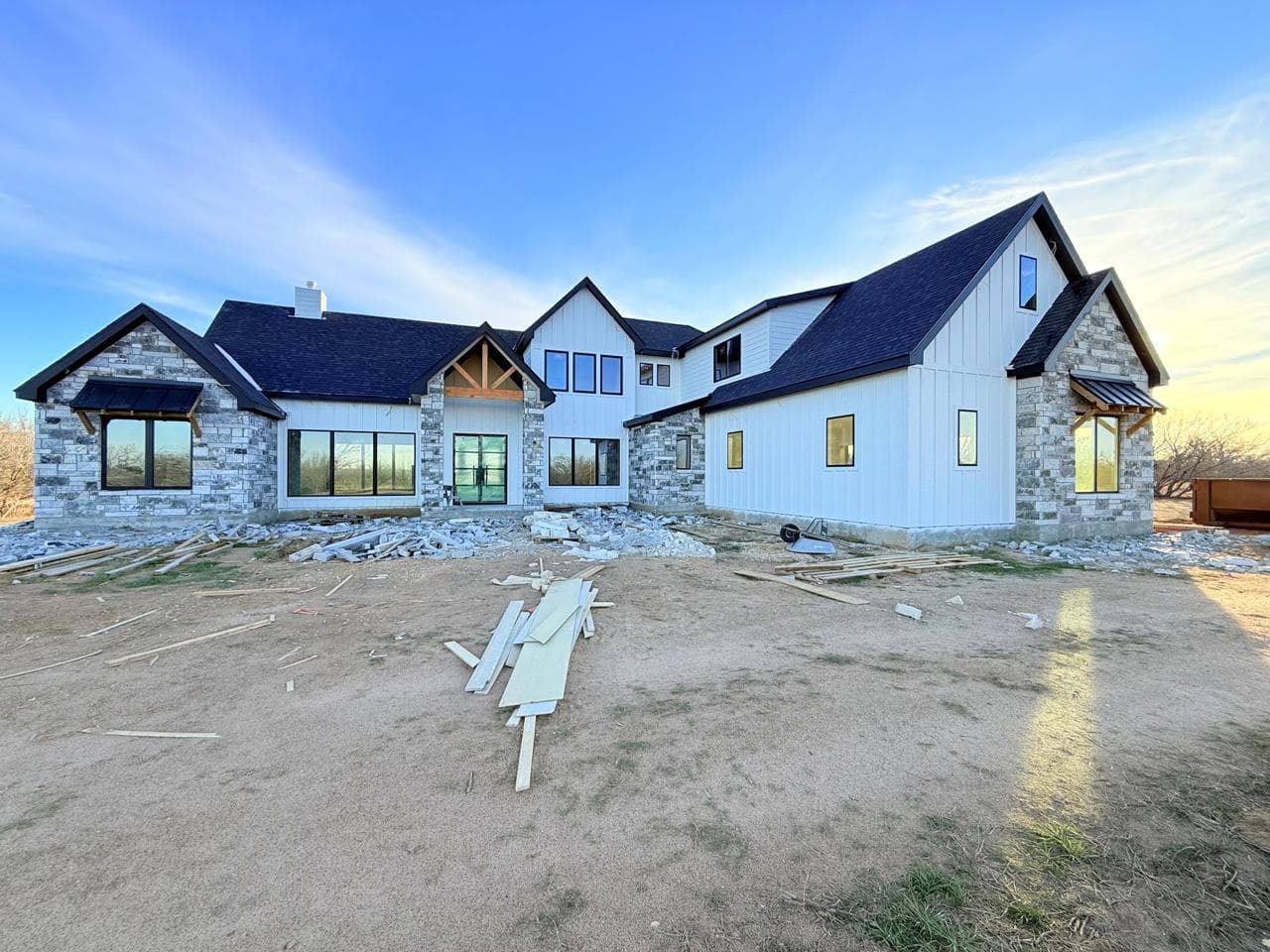 TKG Custom Home under construction - modern farmhouse with stone and board & batten exterior