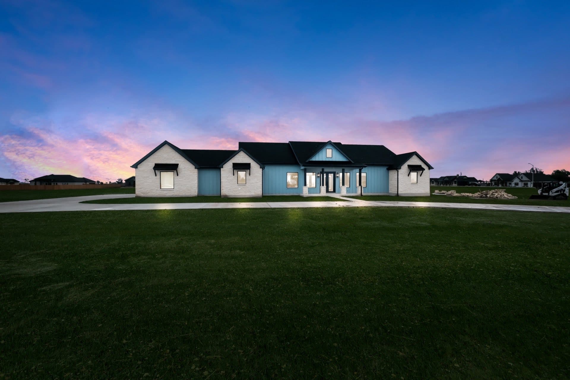 Custom modern farmhouse with stone accents and curved driveway built by TKG Custom Homes